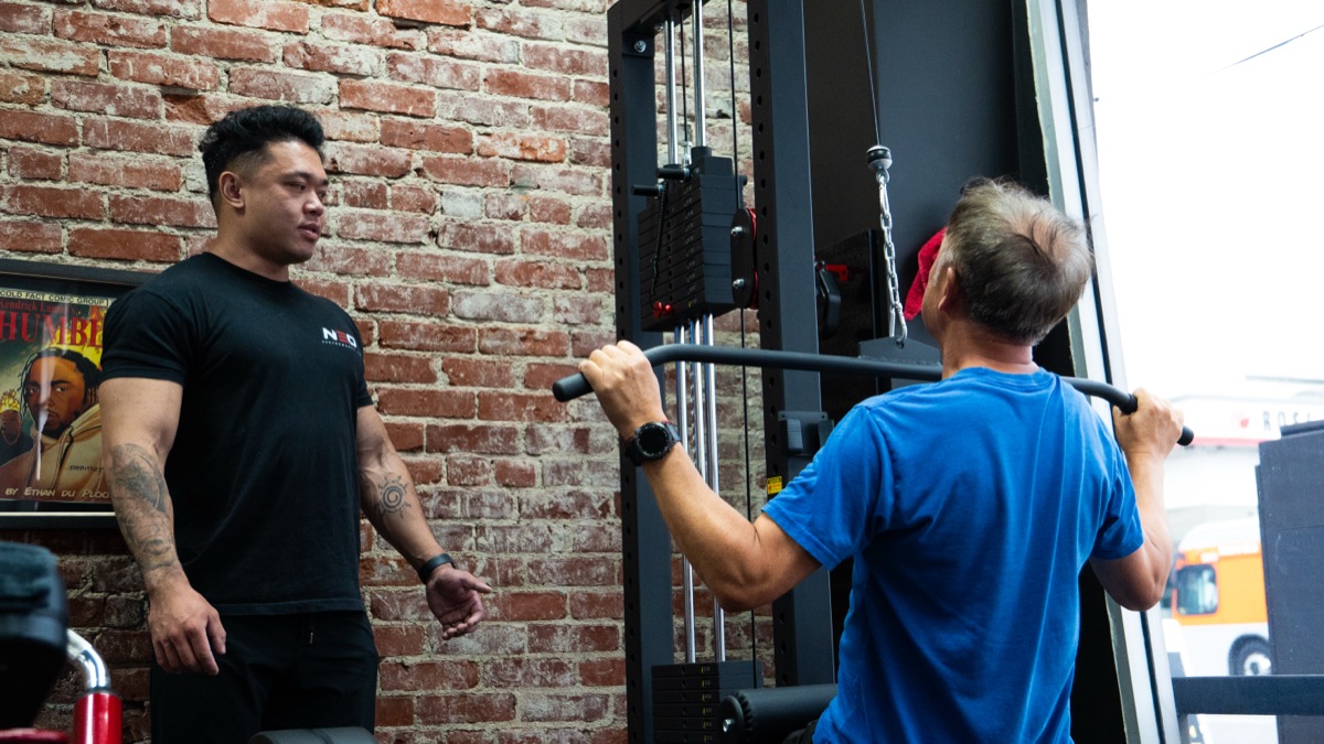 Dr. Kelvin Lee coaching James through a lat pull-down